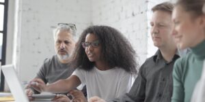 A diverse group of older and younger adults collaborating in a modern, accessible co-working space.