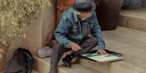 An elderly person sketching a landscape in a peaceful garden.