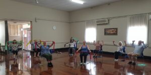 An active senior sitting on a sturdy chair, demonstrating good posture for seated exercises.