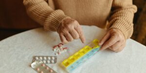 A sunny kitchen table with a pill organizer and a glass of water, representing daily health routines.