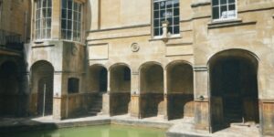 Historic thermal bath resort architecture with stone arches and calm water.