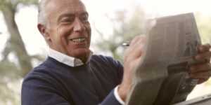 An older adult enjoying a peaceful morning of bird-sketching in a garden.