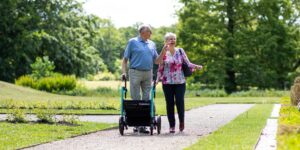 An active senior couple walking through an accessible, sunlit park.