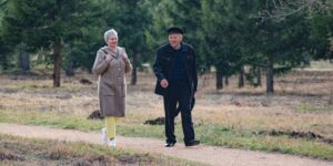 An active senior couple walking on a paved park path.