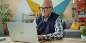 An older adult engaged in focused study at a desk.