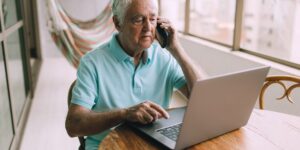 An older adult working confidently on a laptop in a bright, modern home office.