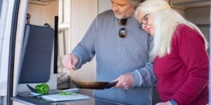 An older couple happily preparing a folate-rich meal with fresh vegetables in a sunny kitchen.