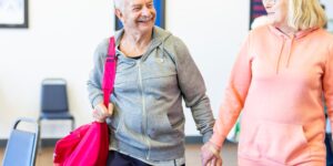 An older couple enjoying a museum tour with comfortable clothing and a walking cane.
