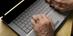 A senior adult performing a seated wrist-flexion exercise with a light weight to build grip strength.