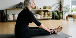 An older adult practicing seated neck mobility exercises in a well-lit, comfortable home environment.