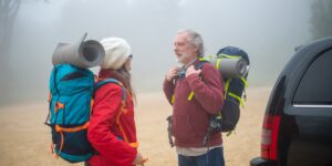 An active senior couple prepared for a mountain day trip on a scenic trail.