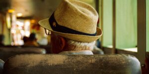 An older traveler enjoying a peaceful train journey while wearing noise-canceling headphones.